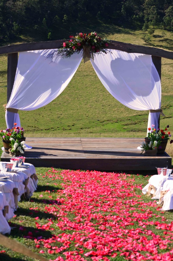 Red Rose Petals leading to a rustic timber stage and archway